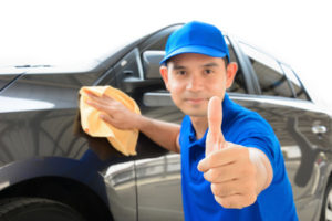A man giving thumbs up while cleaning car, auto detailing (or valeting) concept