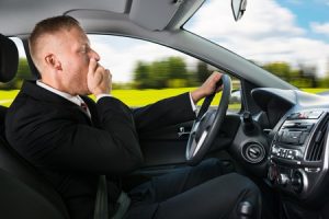 Portrait Of A Young Businessman Yawning While Driving Car