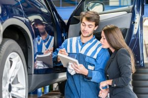 car mechanic with female customer going through collision repair checklist in garage