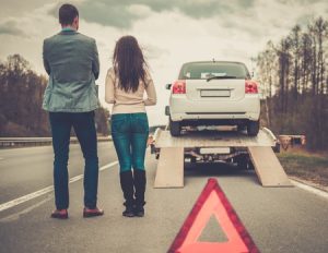 couple near tow-truck picking up broken car use roadside assistance coverage