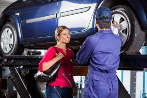 Happy female customer getting repair estimate from auto technician